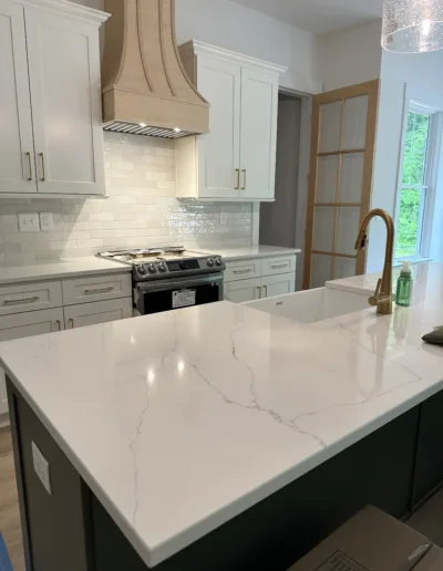 A kitchen with white cabinets and marble counter tops.